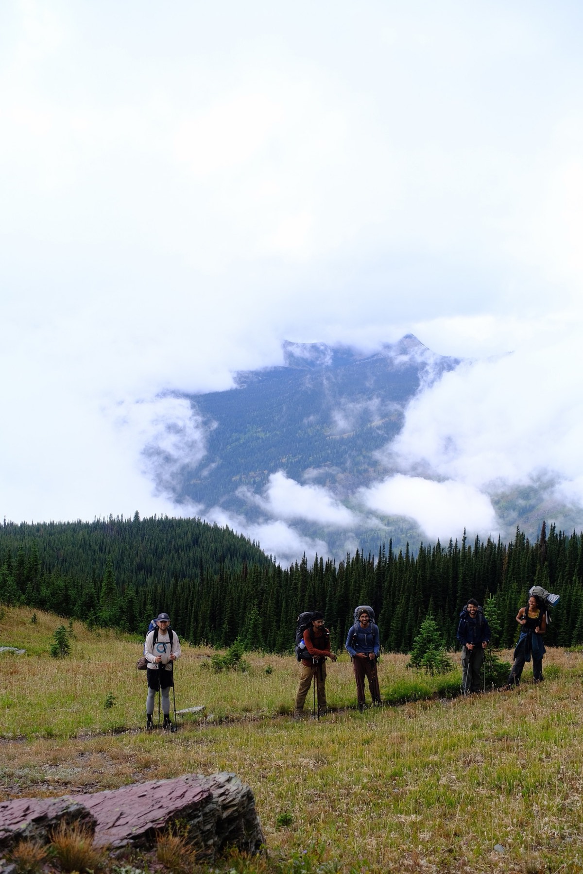 The group standing in a meadow with cloud swallowing the peak behind